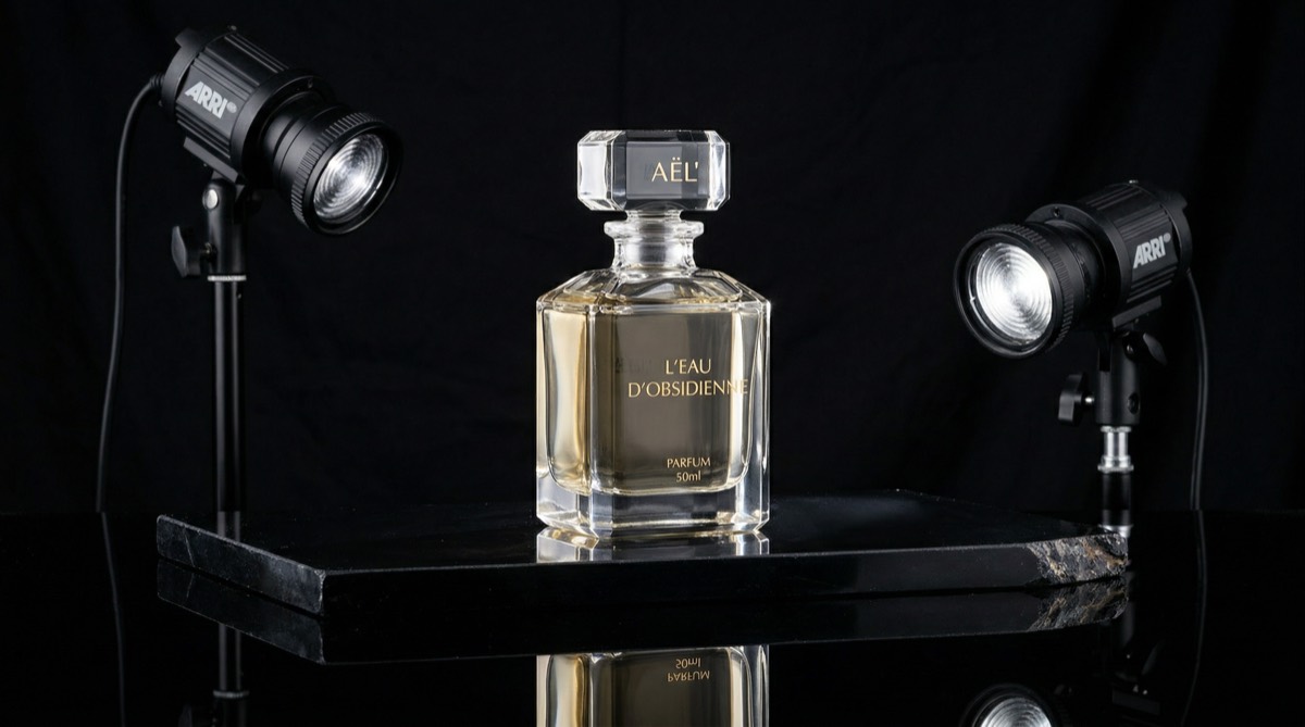 High-end product video set with glass bottle on obsidian surface lit by two Fresnel lights with crisp highlights and black background