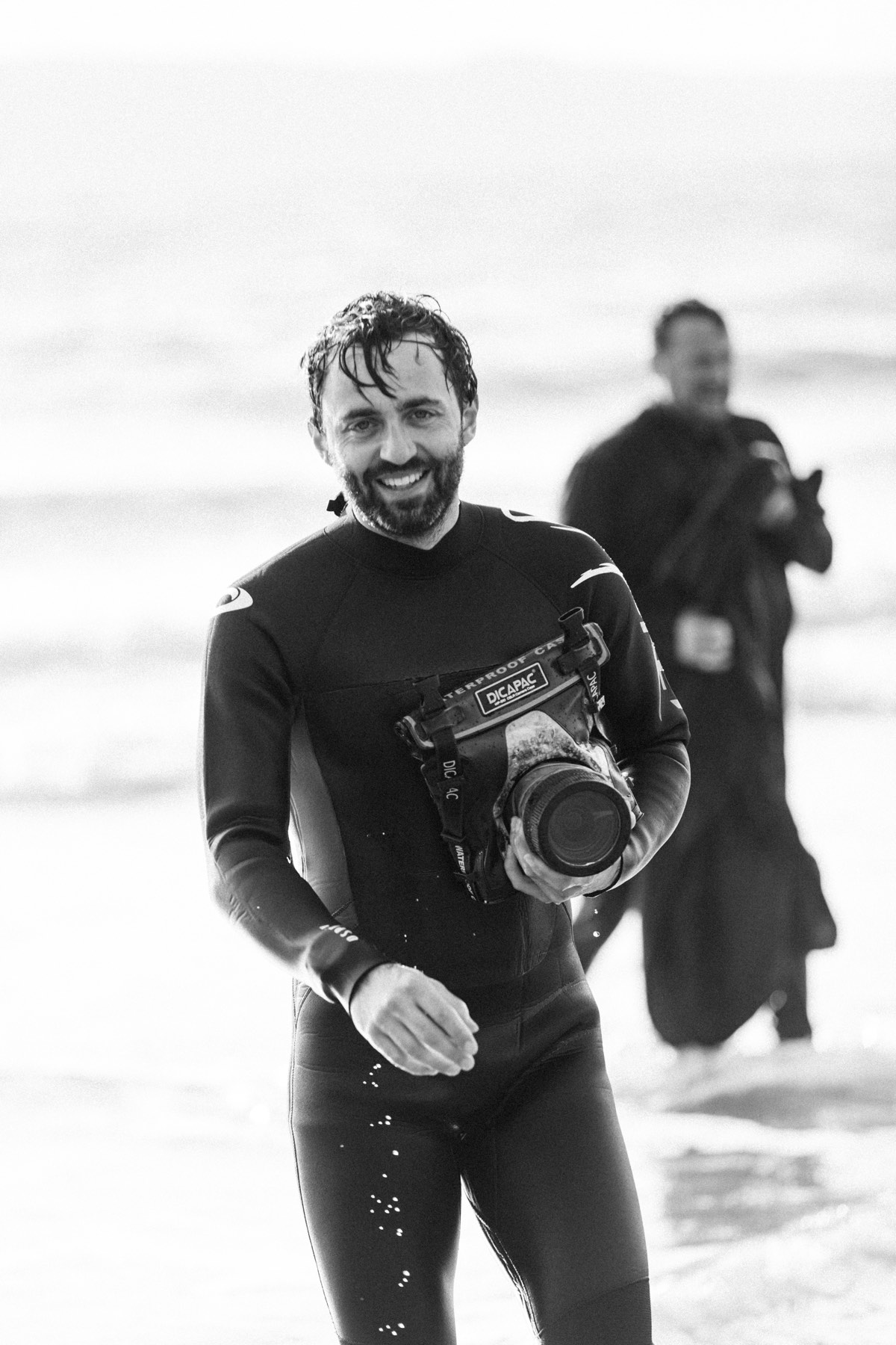 Moss Davis emerging from the sea with camera, black and white portrait