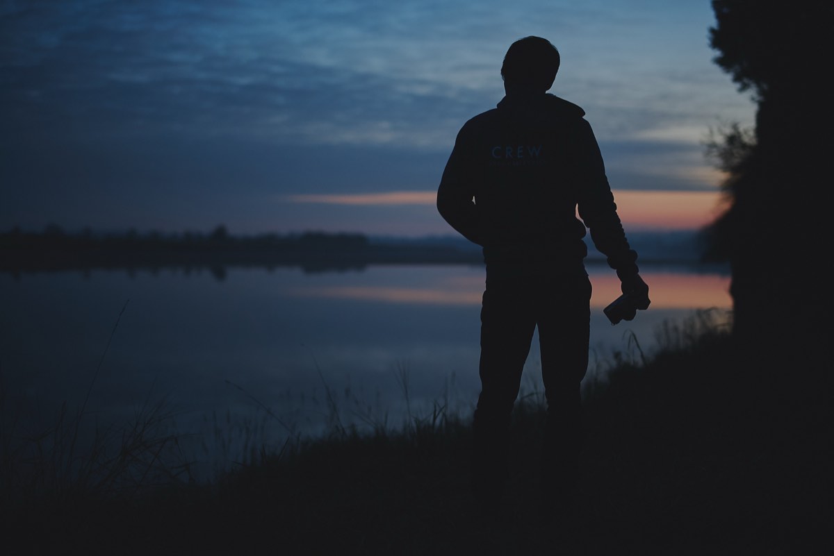 Silhouette of Moss Davis in Singularity Film crew jacket at sunset by a lake
