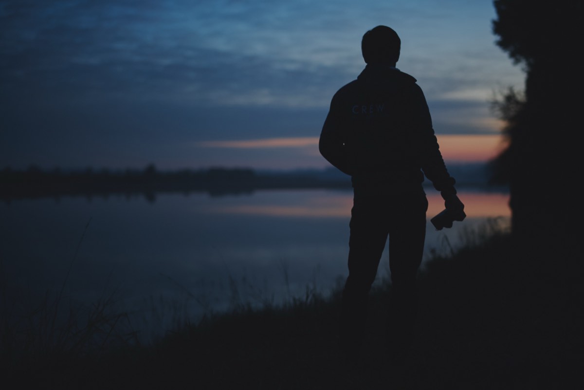 Silhouette of videographer at a lake during golden hour