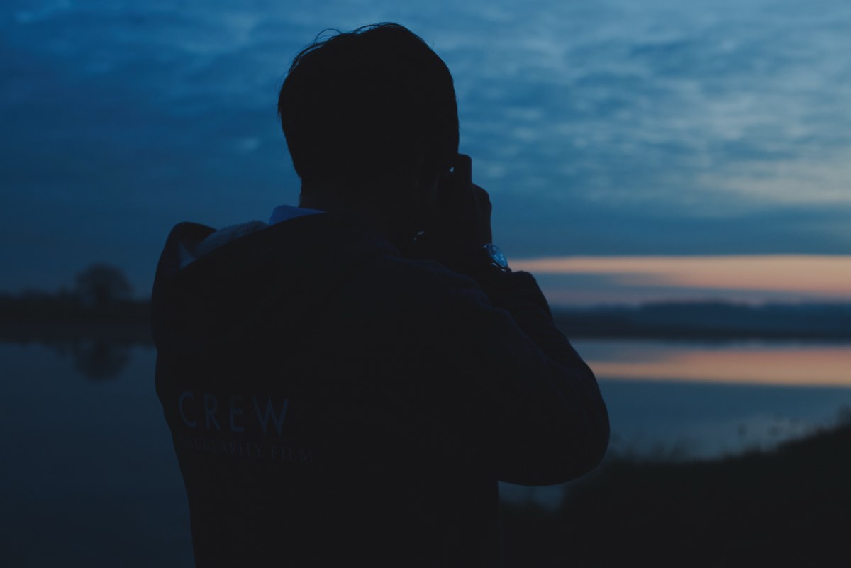 Silhouette of a videographer against a sunset sky