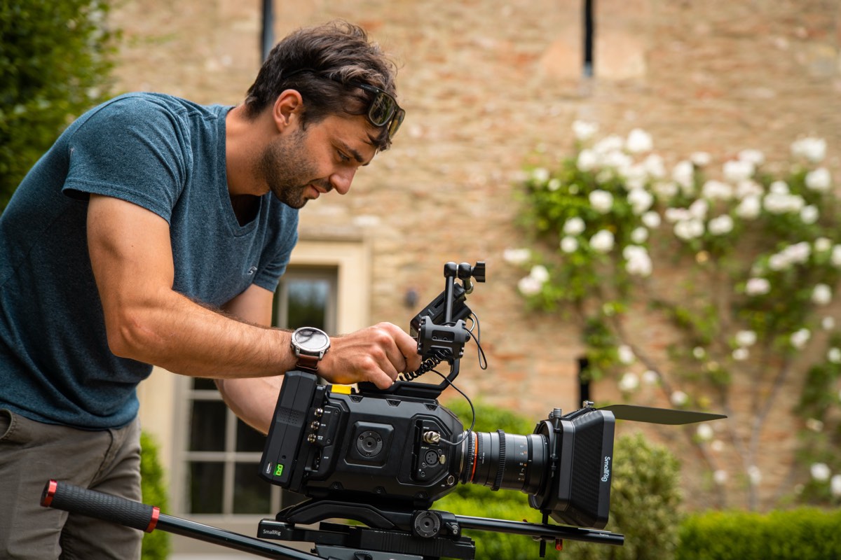 Moss Davis setting up Blackmagic URSA cinema camera outside a Cotswold stone building